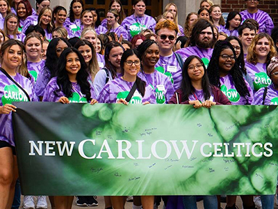 New students in purple tie-dye shirts holding a green sign that says New Carlow Celtics